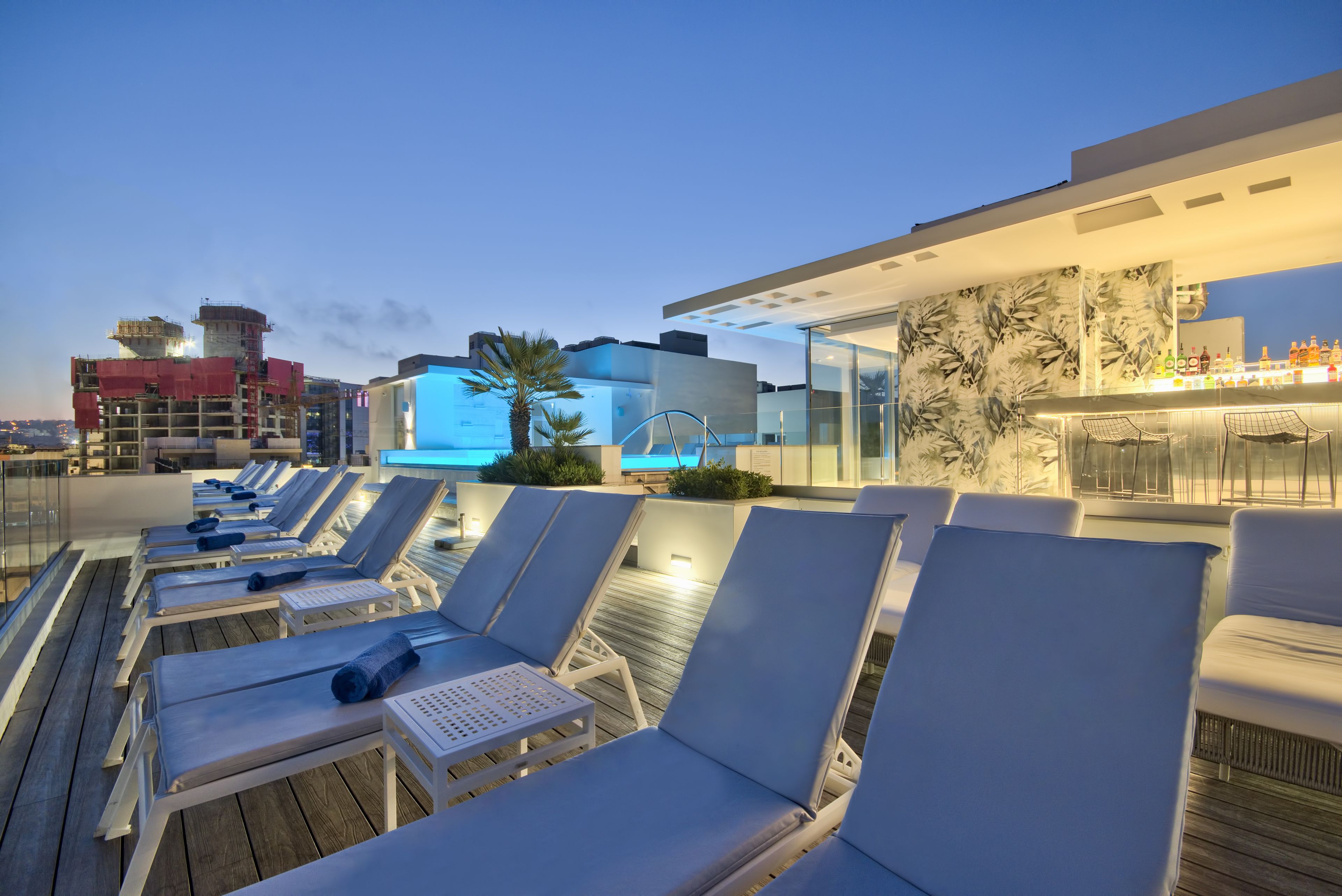 Eine Dachterrasse mit Liegestühlen und einem Pool.