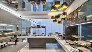 A modern food court with a central island, glass walls, and contemporary lighting. - Hotel Valentina (St. Julian's)