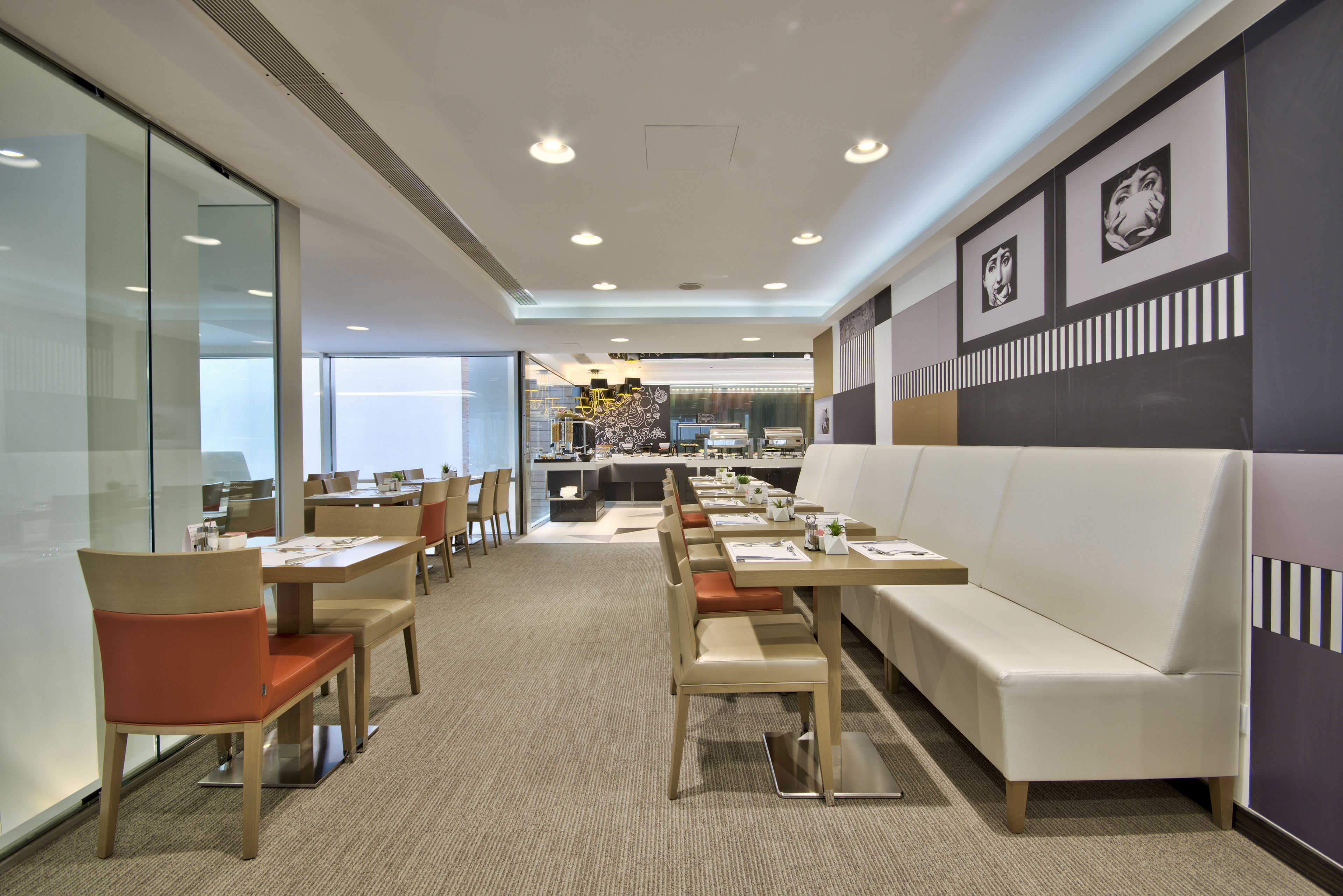Un comedor moderno con paredes de vidrio, una mesa larga con sillas y un sofá blanco.