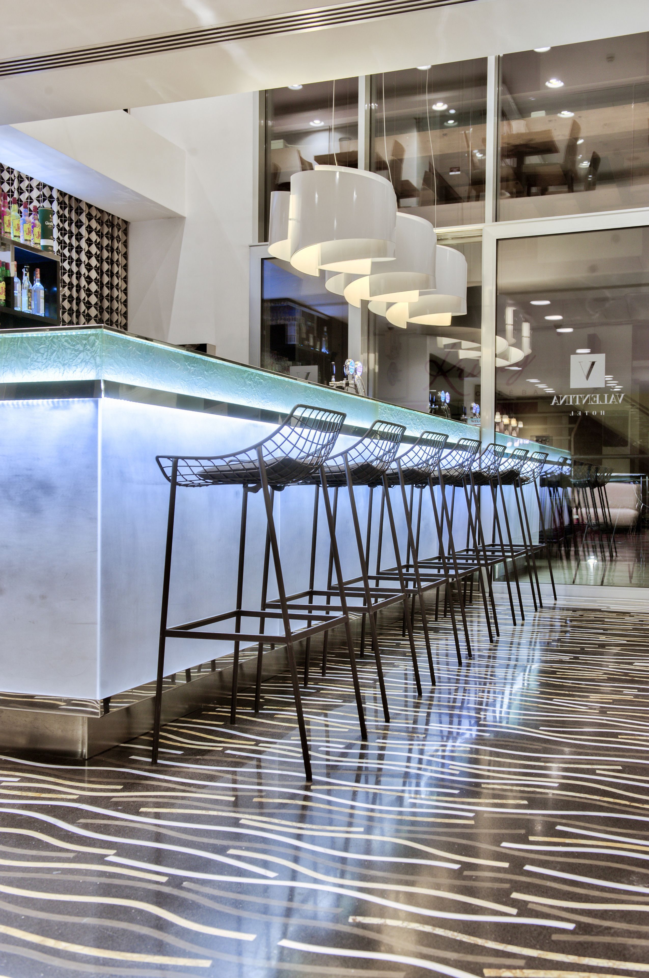 A bar area with a long counter and multiple bar stools.