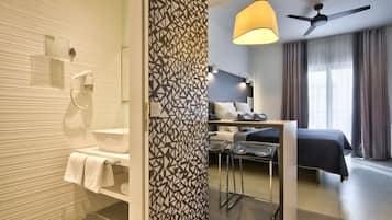 Une chambre d’hôtel moderne équipée d’une douche, d’un lit, d’un bureau et d’un ventilateur de plafond.