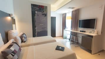 A hotel room with two beds, a desk with a TV, a coffee maker, and a large poster on the wall.