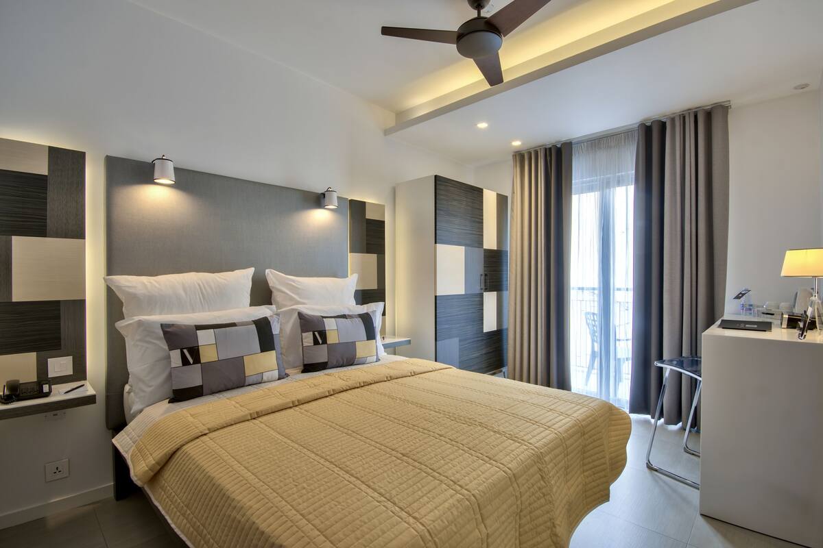 Una moderna camera d'hotel con un letto grande, una scrivania e una ventola a soffitto.