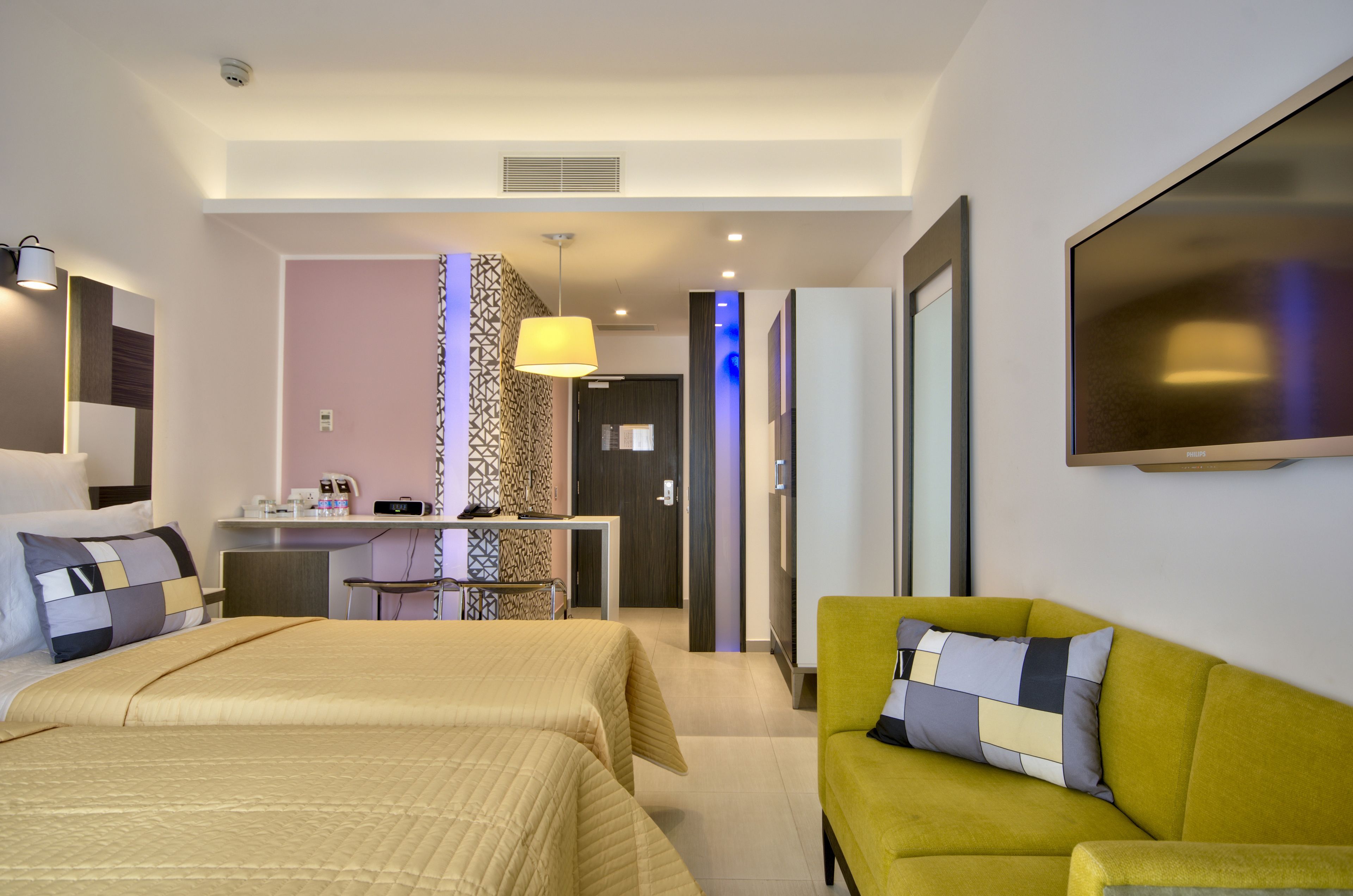 A hotel room with two beds, a sofa, a desk, and a TV.