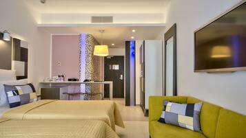 A hotel room with two beds, a sofa, a desk, and a TV.