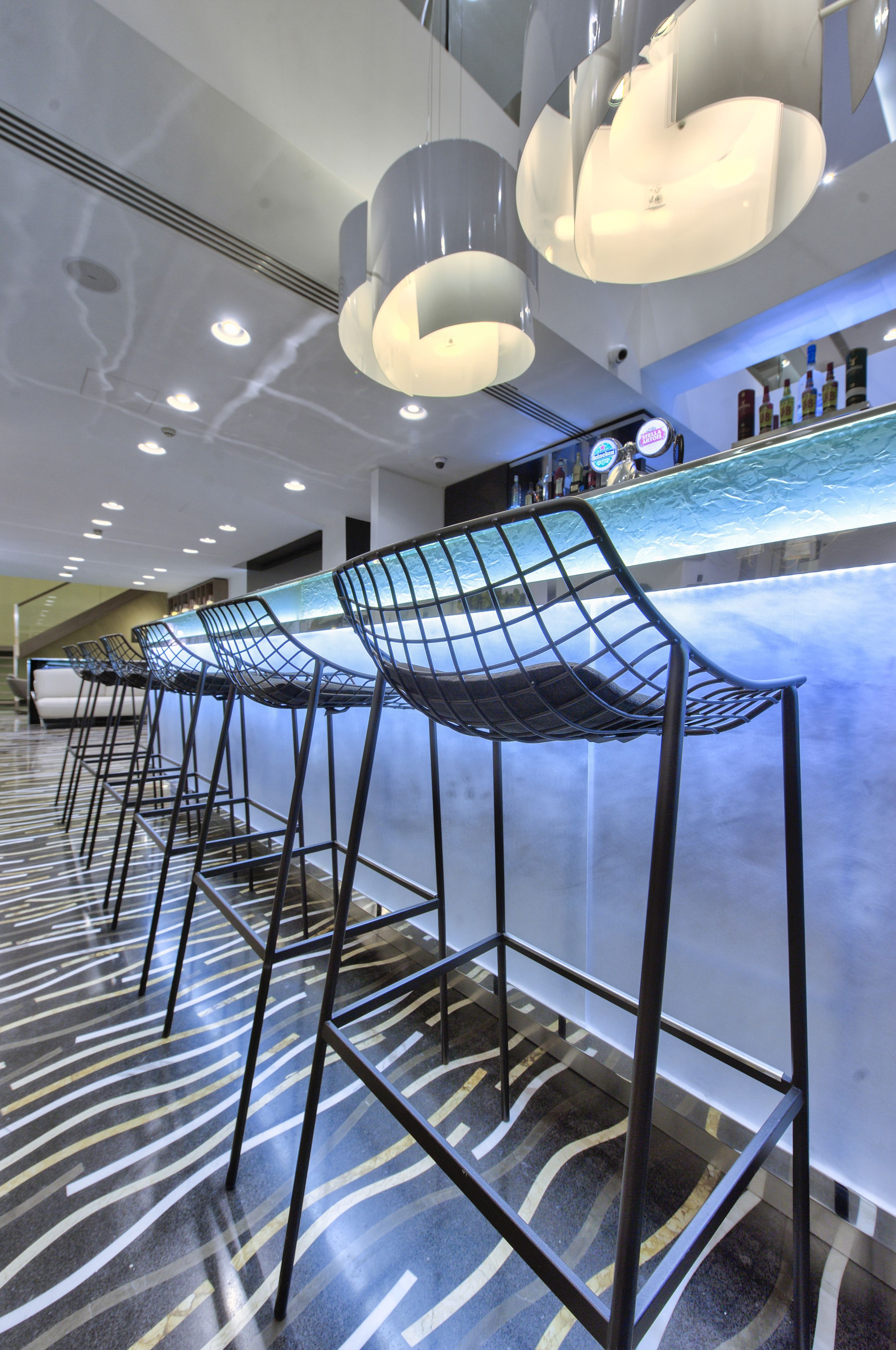 Eine Bar mit Metallhocker und Deckenleuchten.