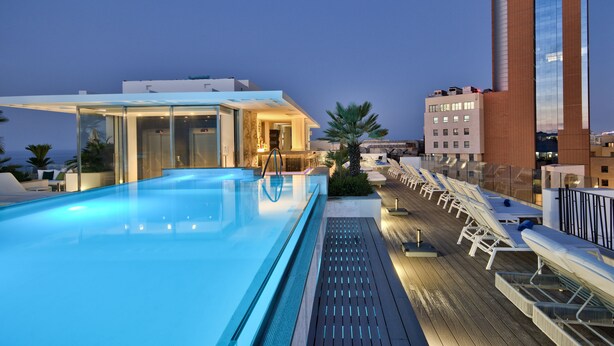 A rooftop pool area with lounge chairs and a glass-enclosed bar. - Hotel Valentina (St. Julian's)