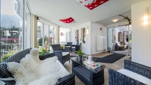 A spacious room with wicker furniture, a glass table, and a view of the outdoors.