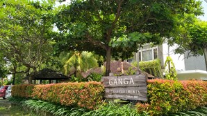 A wooden sign for Ganga Hotel Apartments with a lush green hedge in the foreground. - Ganga Hotel & Apartments (Denpasar)