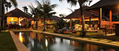 Una piscina al aire libre, sillones reclinables de piscina