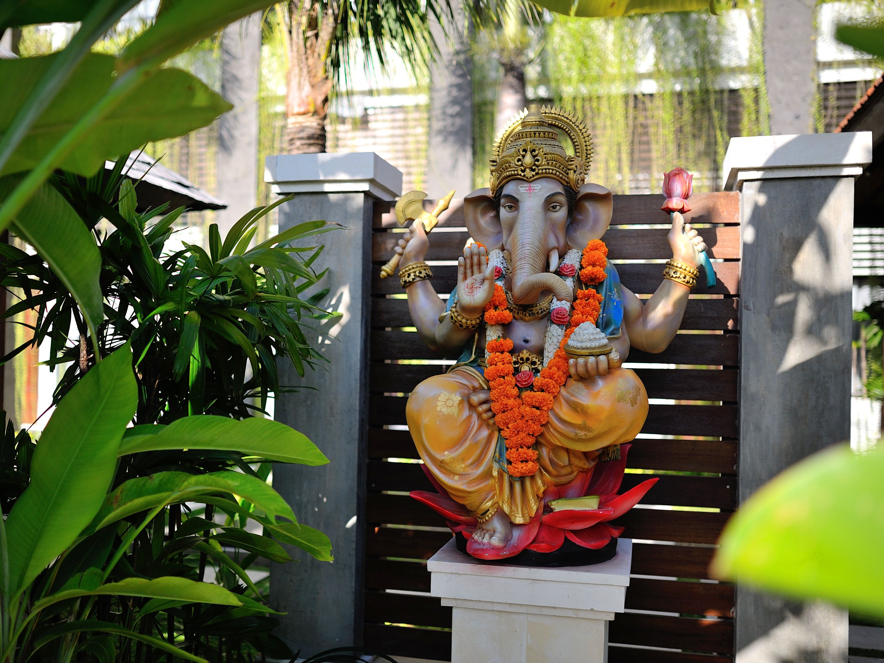 A statue of a deity with multiple arms, adorned with garlands and jewelry, seated on a lotus base.