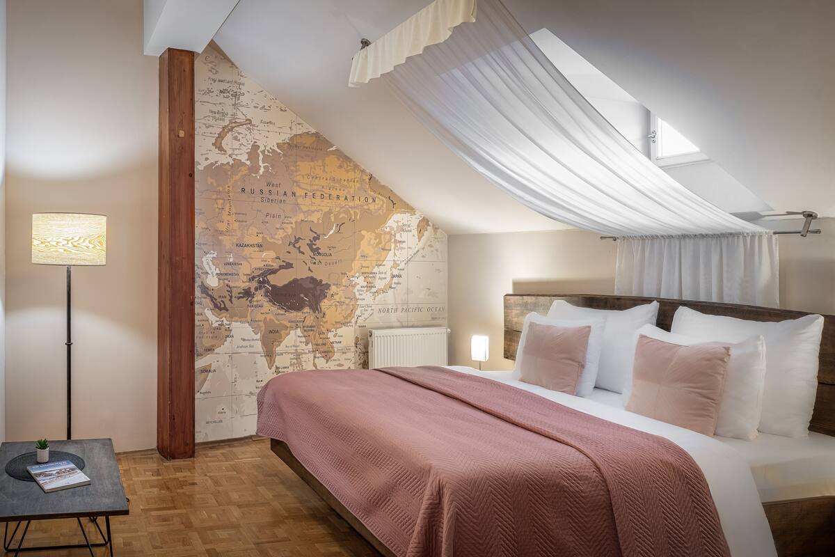 Ein Schlafzimmer mit einem großen Bett, einer Wandkarte, einer Stehlampe und einem kleinen Tisch mit einer Pflanze.