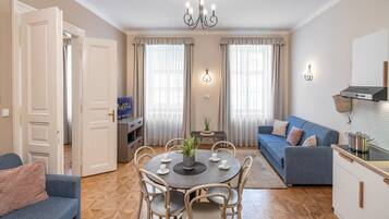 Una sala de estar moderna con comedor, sofá, televisión y una cocina con estufa.