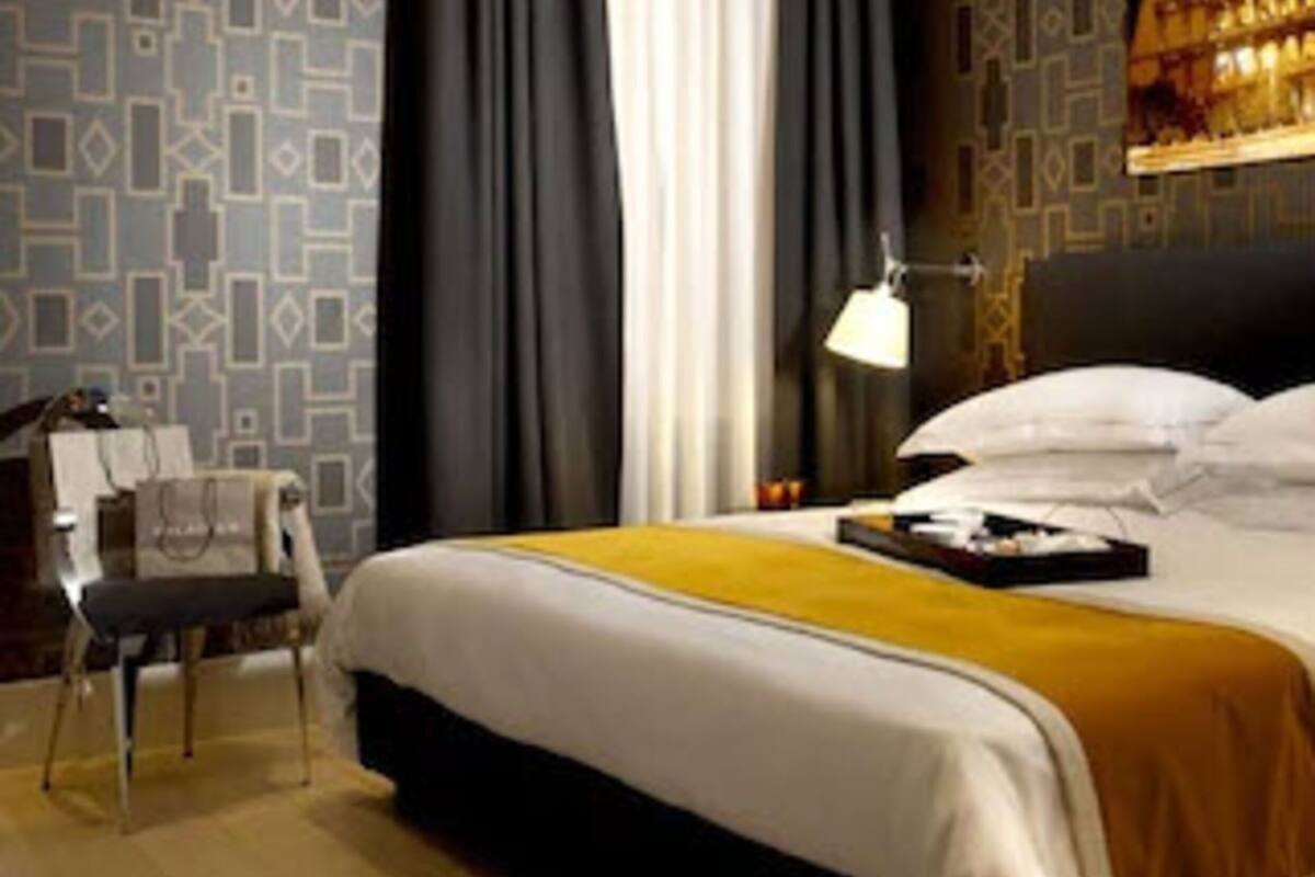 A modern hotel room with a large bed, a desk, and a chair.