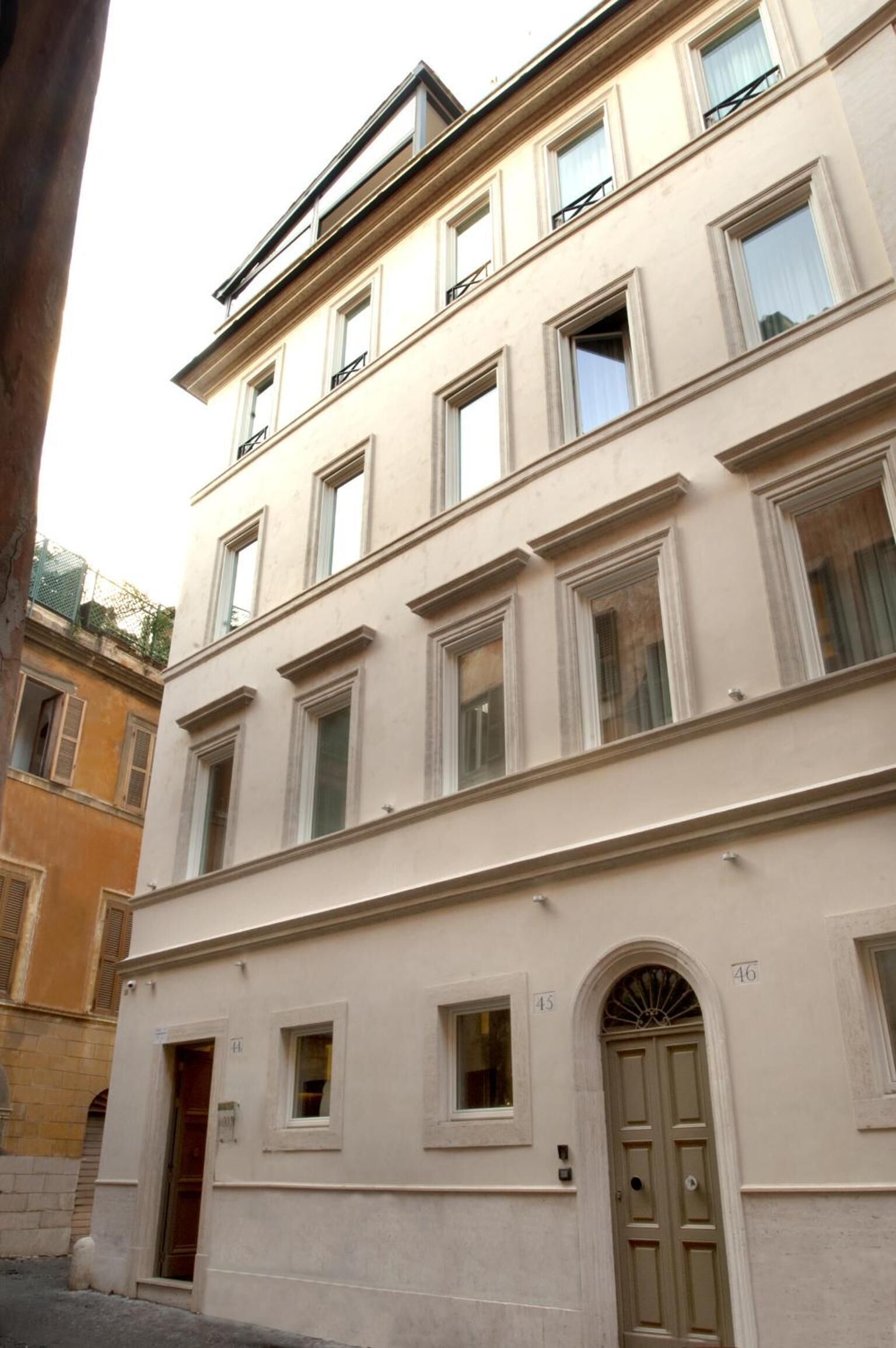 Un edificio de varios pisos con fachada beige, ventanas numeradas y una entrada central en arco.