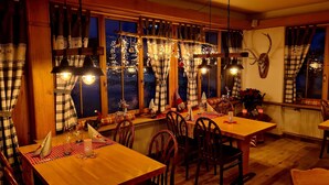 Een gezellig verlicht eetgedeelte met geruite gordijnen, houten meubels en feestelijke decoraties.