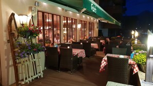 Een terrasrestaurant met rieten meubilair en rood-witte geruit tafelkleed.