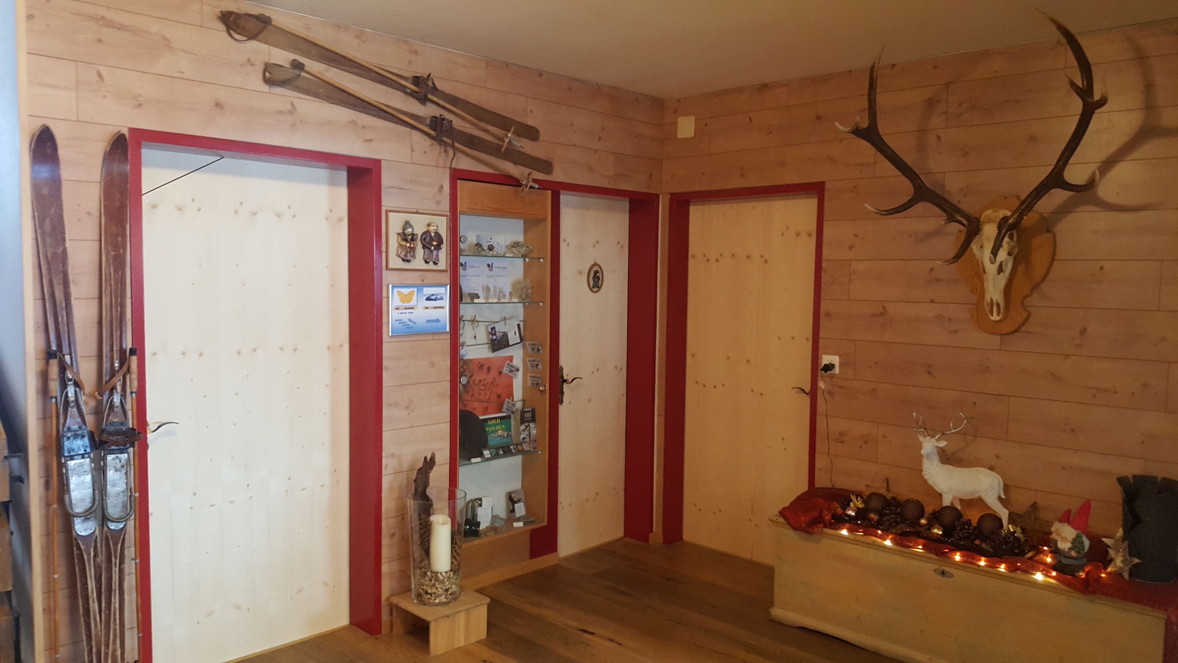 Un interior de madera con un esquí de pared, una cabeza de venado montada y un estante con diversos objetos.
