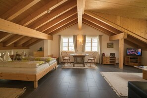 Une chambre spacieuse aménagée en mezzanine, avec un grand lit, une table à manger avec des chaises et un téléviseur dans un coin.