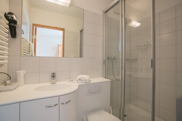 A modern bathroom with a white sink, mirror, and glass shower enclosure.