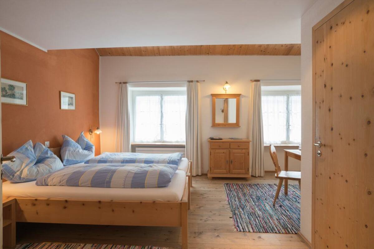 Ein Schlafzimmer mit einem Bett, einem Holzschrank, einem Schreibtisch und einem Stuhl.