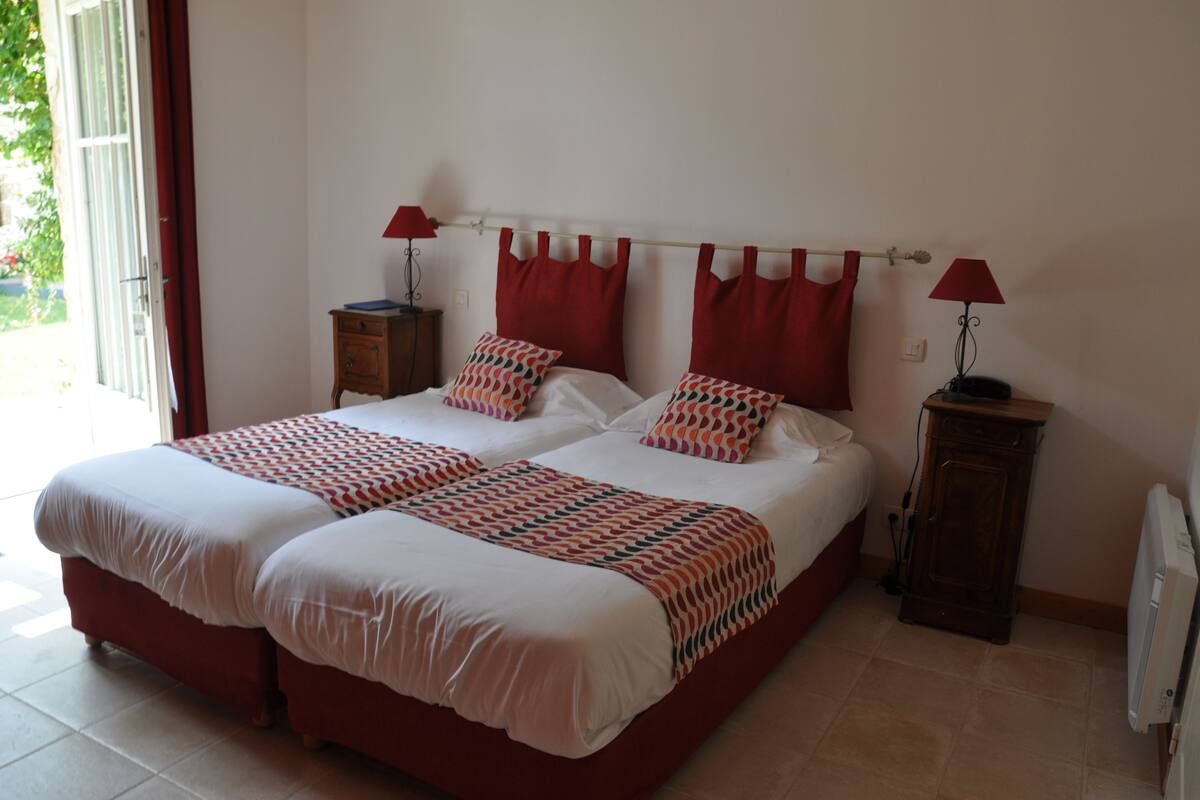 A double bed with a patterned bedspread, two bedside tables with lamps, and a view of the outdoors through a sliding door.