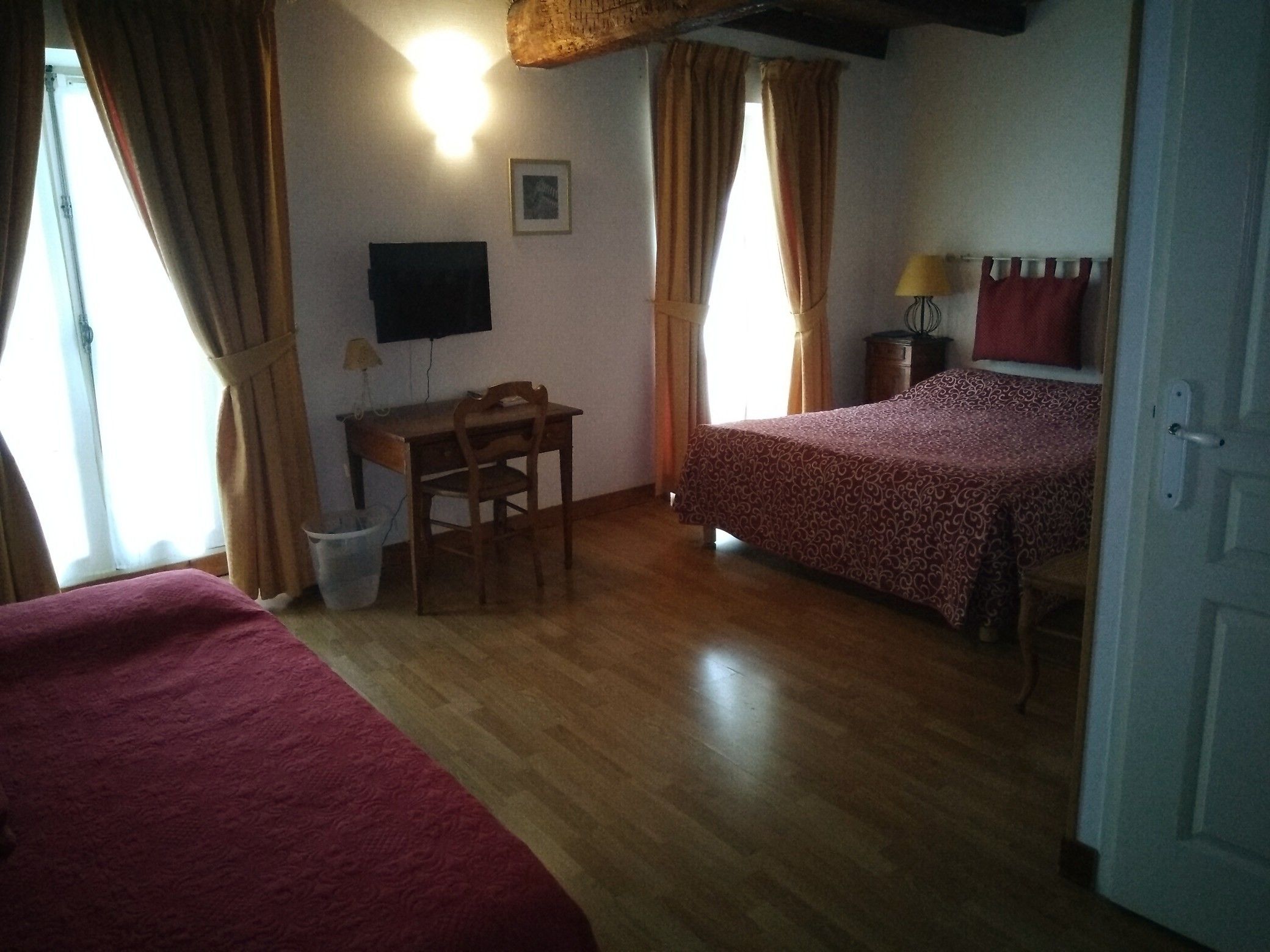 Ein Zimmer mit zwei Betten, einem Schreibtisch, einem Stuhl, einem Fernseher und einer Lampe.