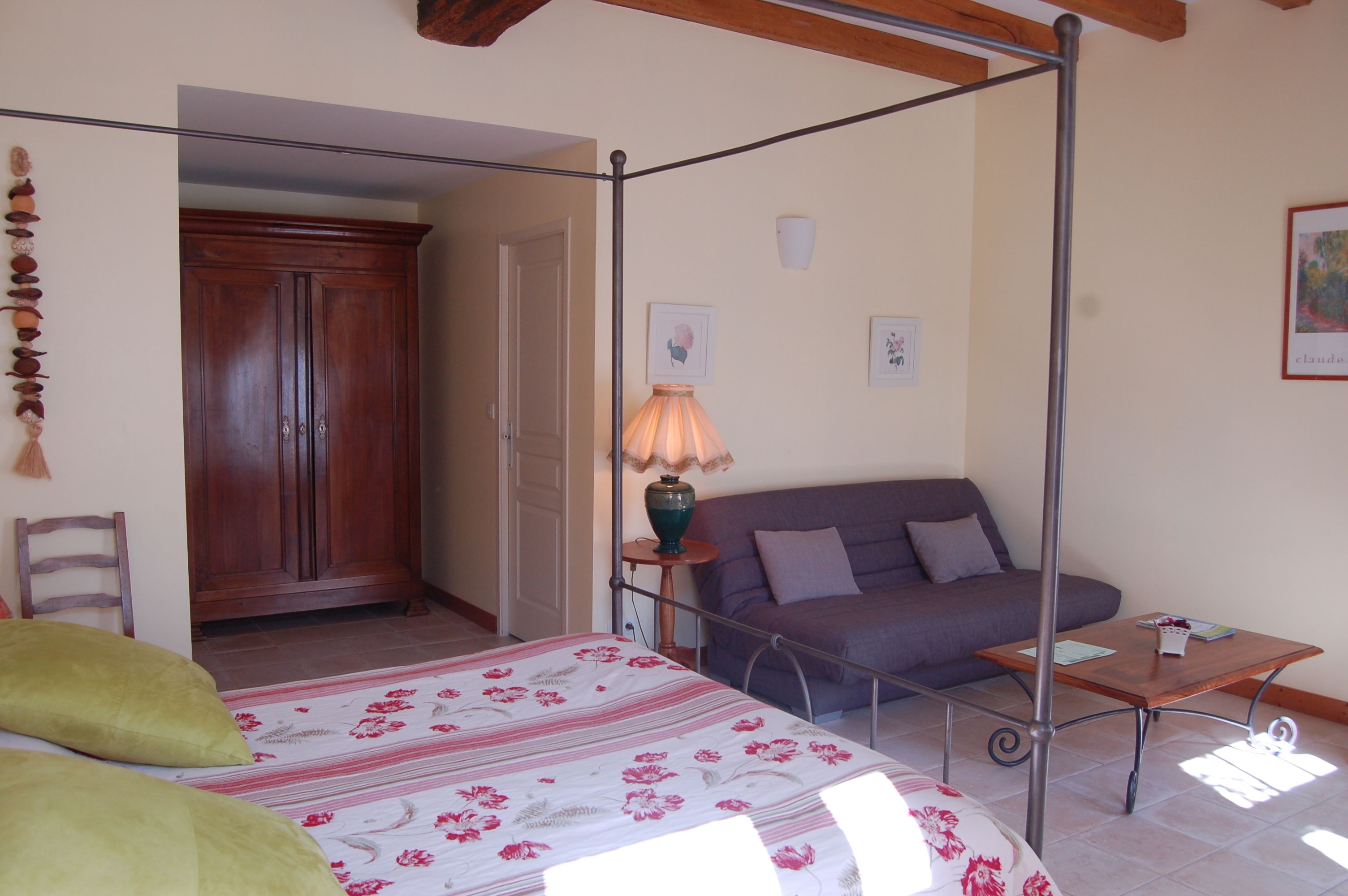 A bedroom with a four-poster bed, a sofa, a small table, and a cabinet.