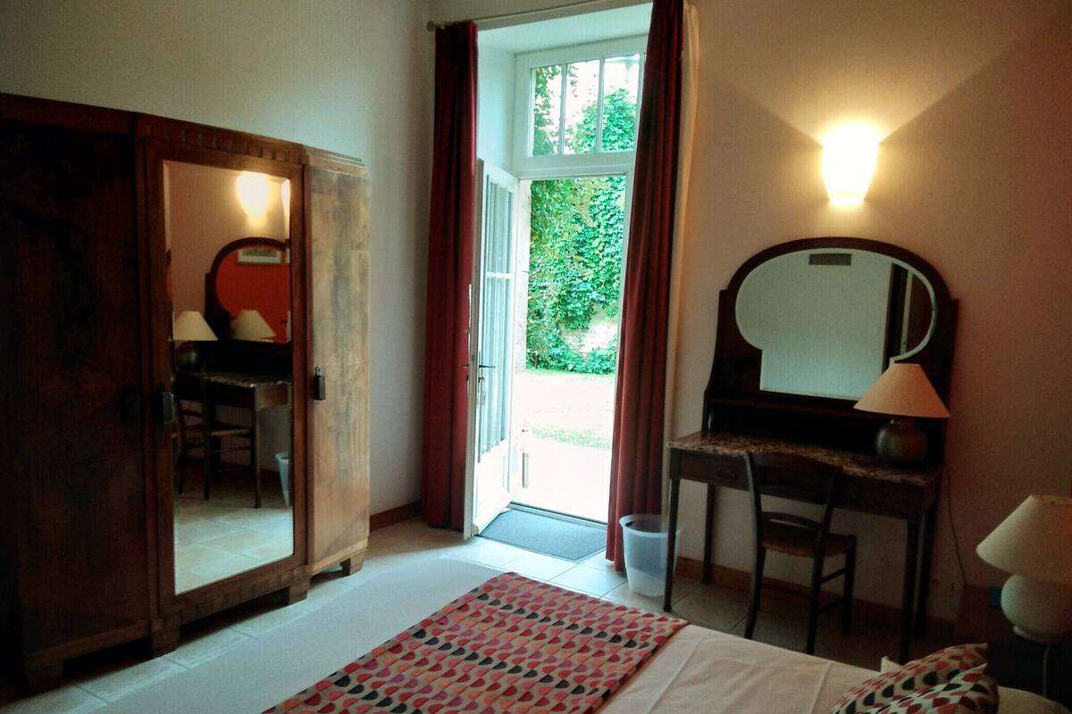 A bedroom with a bed, a desk, a chair, a wardrobe, and a mirror.