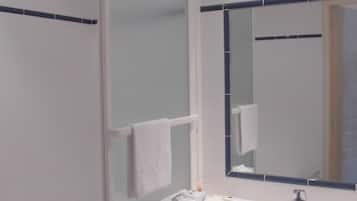 A modern bathroom with a white bathtub, a sink with a mirror above it, and a towel rack.