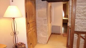 A narrow hallway with a wooden door, a lamp, and a stone wall.