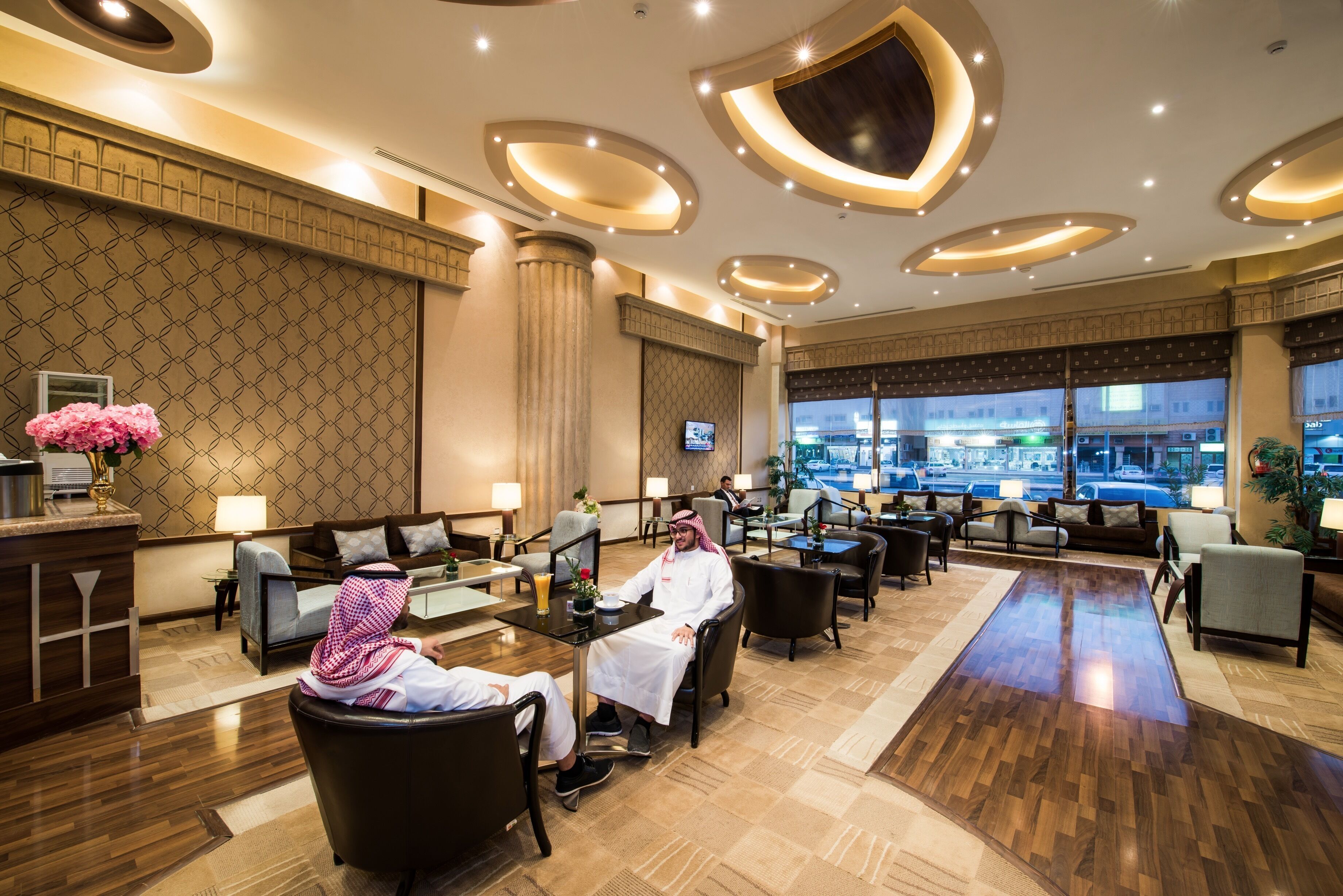 A spacious lobby with a modern design, featuring a large seating area, a reception desk, and large windows offering a view of the city.