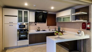 A modern kitchen with built-in appliances, a central island, and a fire extinguisher on the wall. - Boudl Rass (Ar Rass)