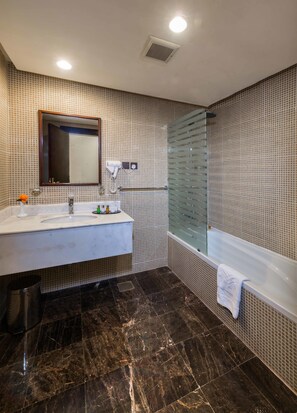 A modern bathroom with a large mirror, a sink, a vanity, a glass shower enclosure, and a bathtub.