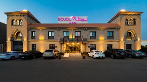 A hotel with a prominent sign, multiple cars parked in front, and a well-lit entrance. - Boudl Rass (Ar Rass)
