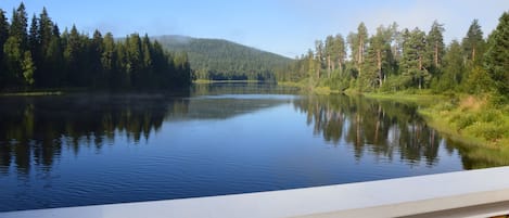 Um lago calmo com uma montanha arborizada ao fundo.