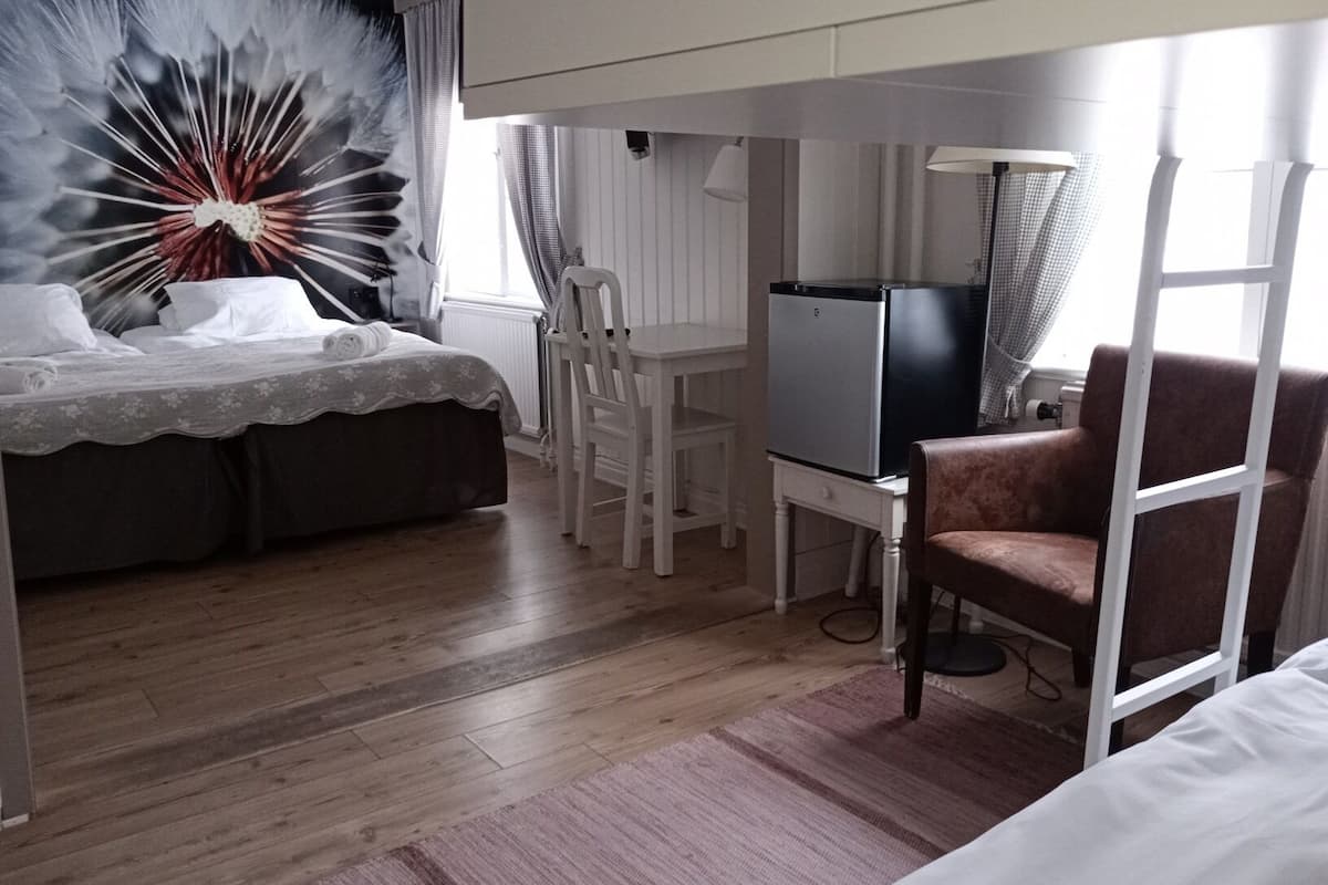 Una habitación de hotel con cama, escritorio, silla, televisión y ventana.