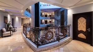 A modern hotel lobby with a central atrium, a decorative railing, and a staircase leading to upper floors. - Boudl Al Fakhria (Unaizah)
