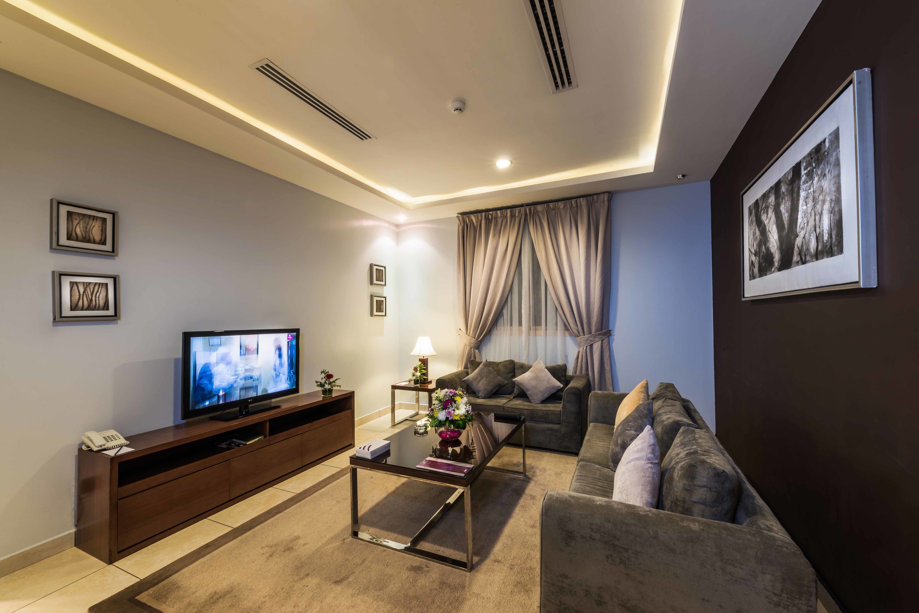 A modern living room with a flat-screen TV, a sofa, a coffee table, and a TV stand.