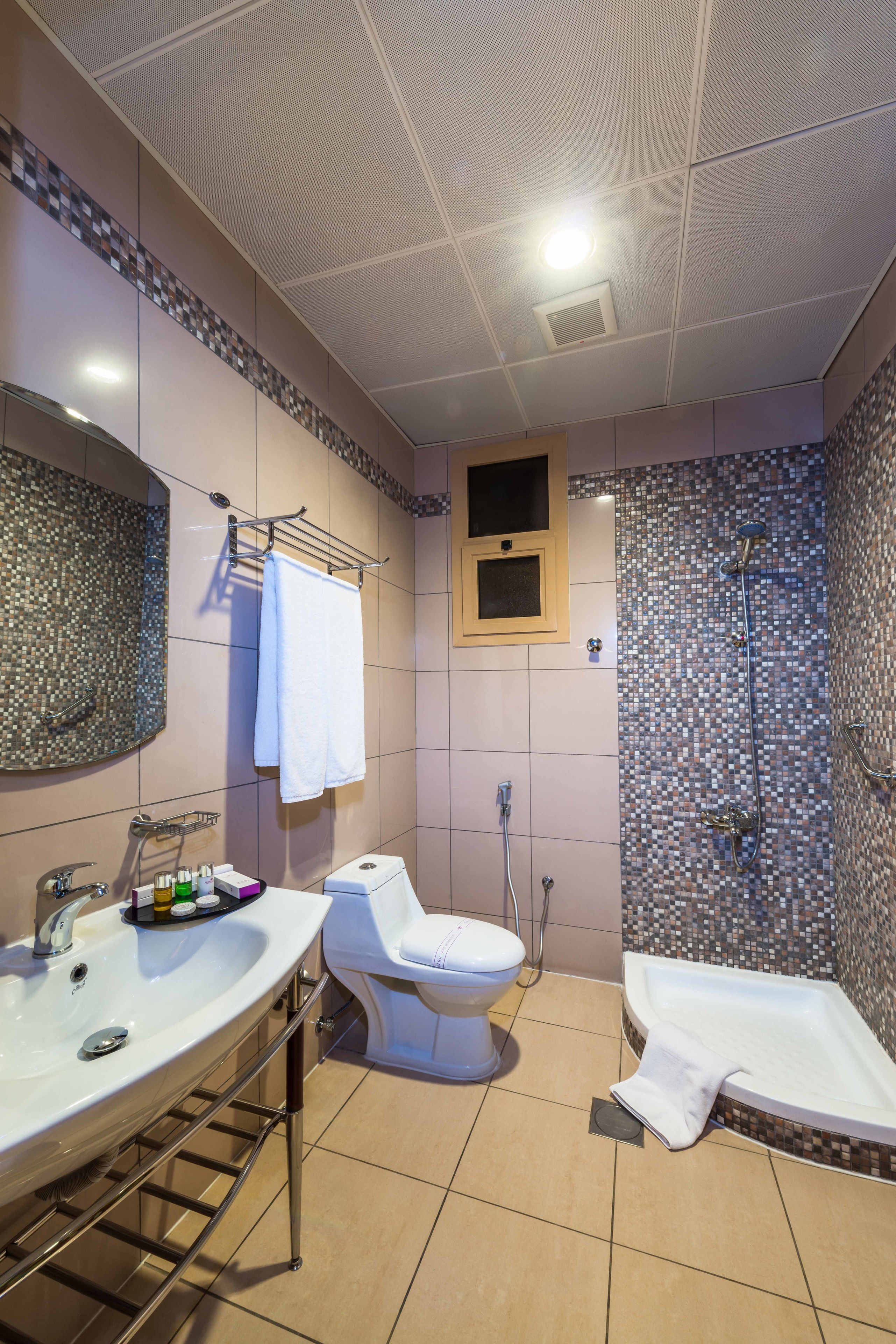 A bathroom with a shower, toilet, and sink.