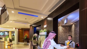 A hotel lobby with a reception desk, seating area, and a view of the street outside. - Boudl Al Fakhria (Unaizah)