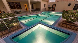 A swimming pool with a tiled deck and a glass railing. - Boudl Al Fakhria (Unaizah)