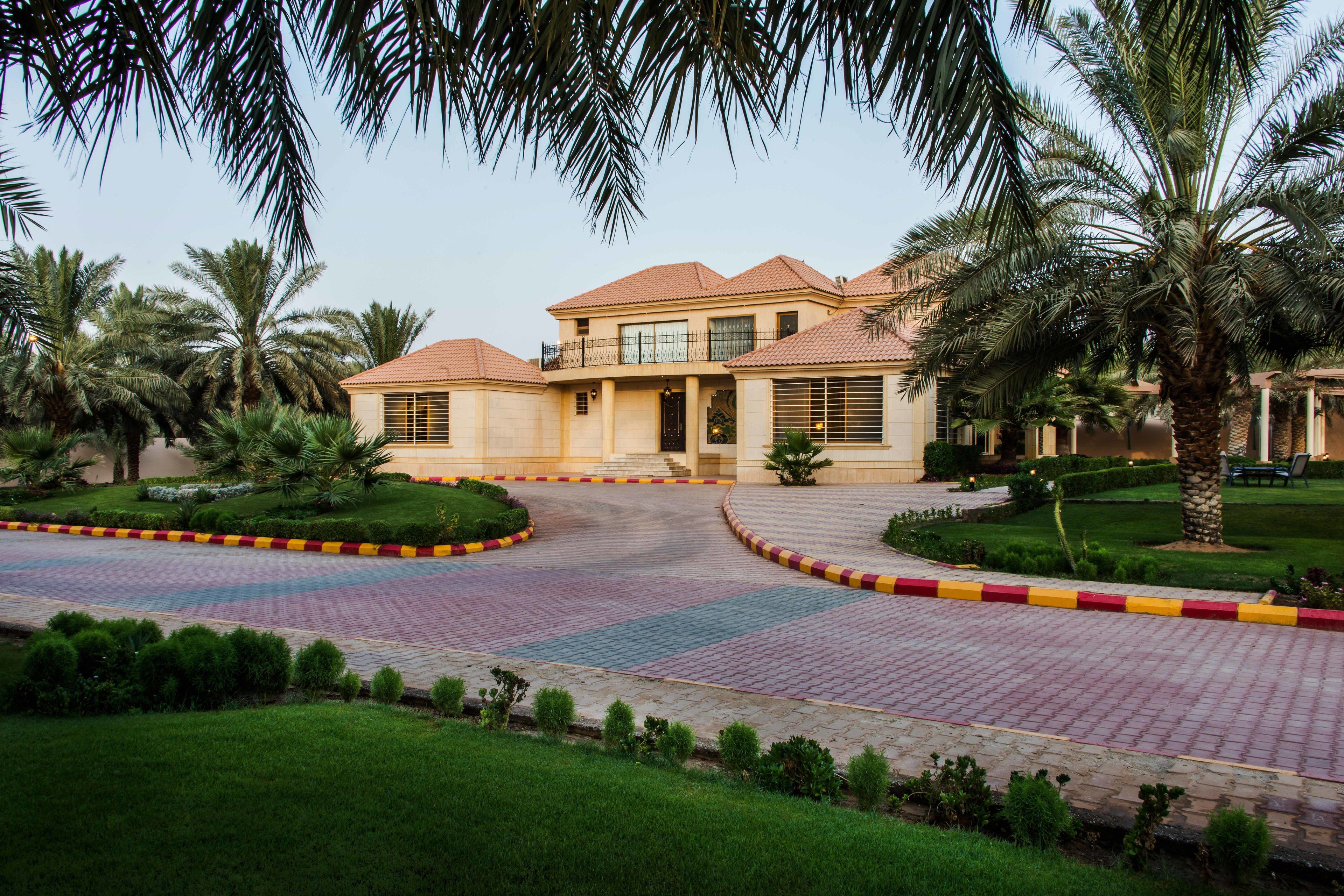 A two-story building with a tiled roof, surrounded by palm trees and a landscaped garden.