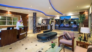 A hotel lobby with a reception desk, seating area, and a view of the street outside. - Boudl Nakhil  (Unaizah)