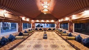 A spacious room with a patterned carpet, a central table, and seating along the walls. - Boudl Nakhil  (Unaizah)