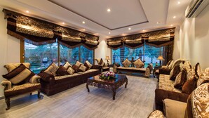 A spacious living room with a large sofa set, a coffee table, and a view of a pool. - Boudl Nakhil  (Unaizah)