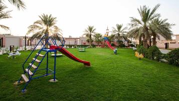 Children can play safely in this well-maintained outdoor area with a slide, climbing structure, and swing set.