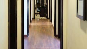 A hallway with wooden flooring, black-framed doors, and a framed picture on the wall. - Boudl Kuwait (Salmiya)