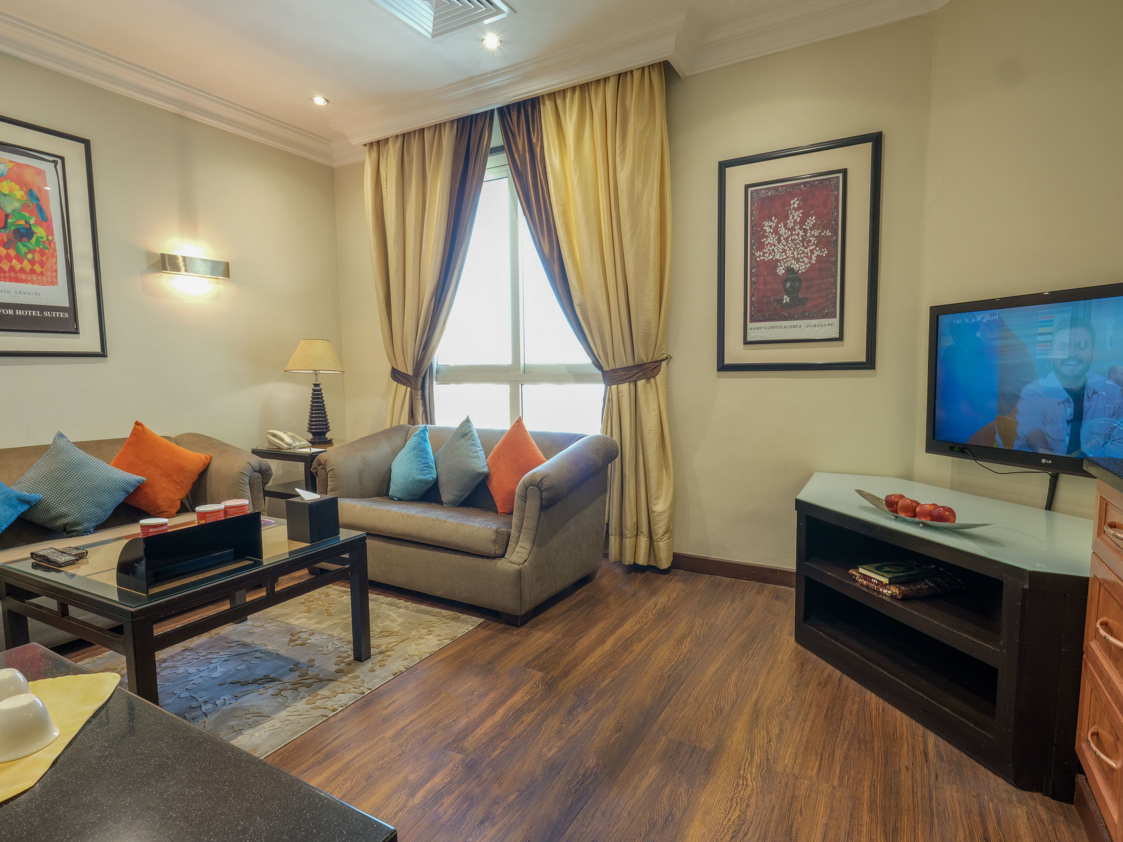 A living room with a sofa, coffee table, TV, and artwork on the walls.