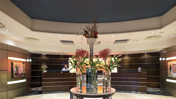 A lobby with a reception desk, a decorative table with vases, and a ceiling with a starry design. - Boudl Kuwait (Salmiya)